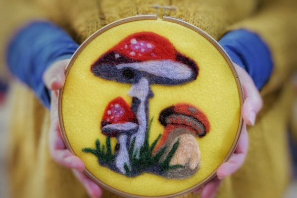 ricamo di funghi stile pop art con lana cardata su pannolenci giallo e incorniciato con un telaio da ricamo tondo
