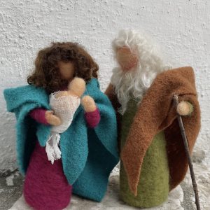 Natività stile Waldorf in lana cardata, Maria tiene in mano il piccolo Gesù avvolto da una garza bianca e accanto c'è Giuseppe che li abbracci
