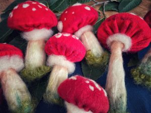 funghi amanita con cappuccio rosso, realistici in lana cardata su panno blu
